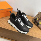 Pair of black unisex sneakers with white laces and chunky white soles.