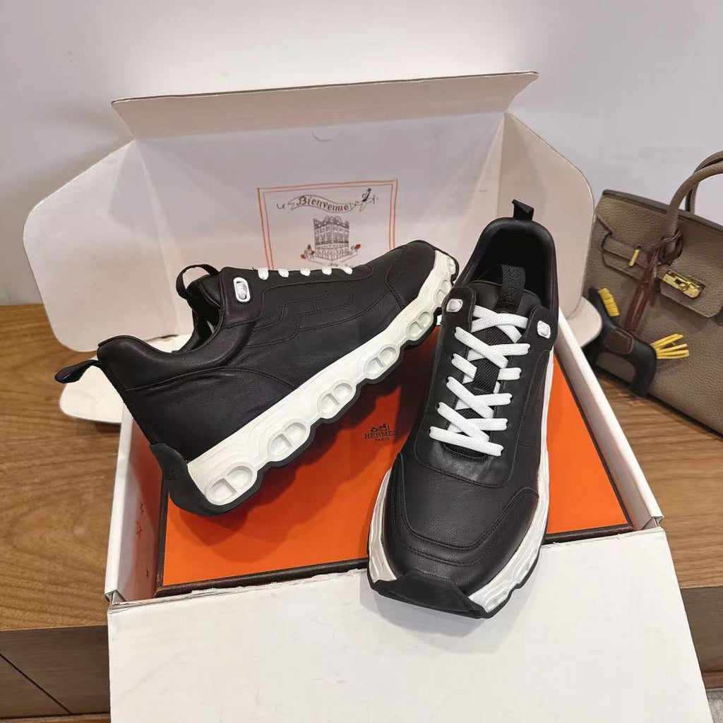 Black unisex sneakers with white laces and sculpted thick sole.