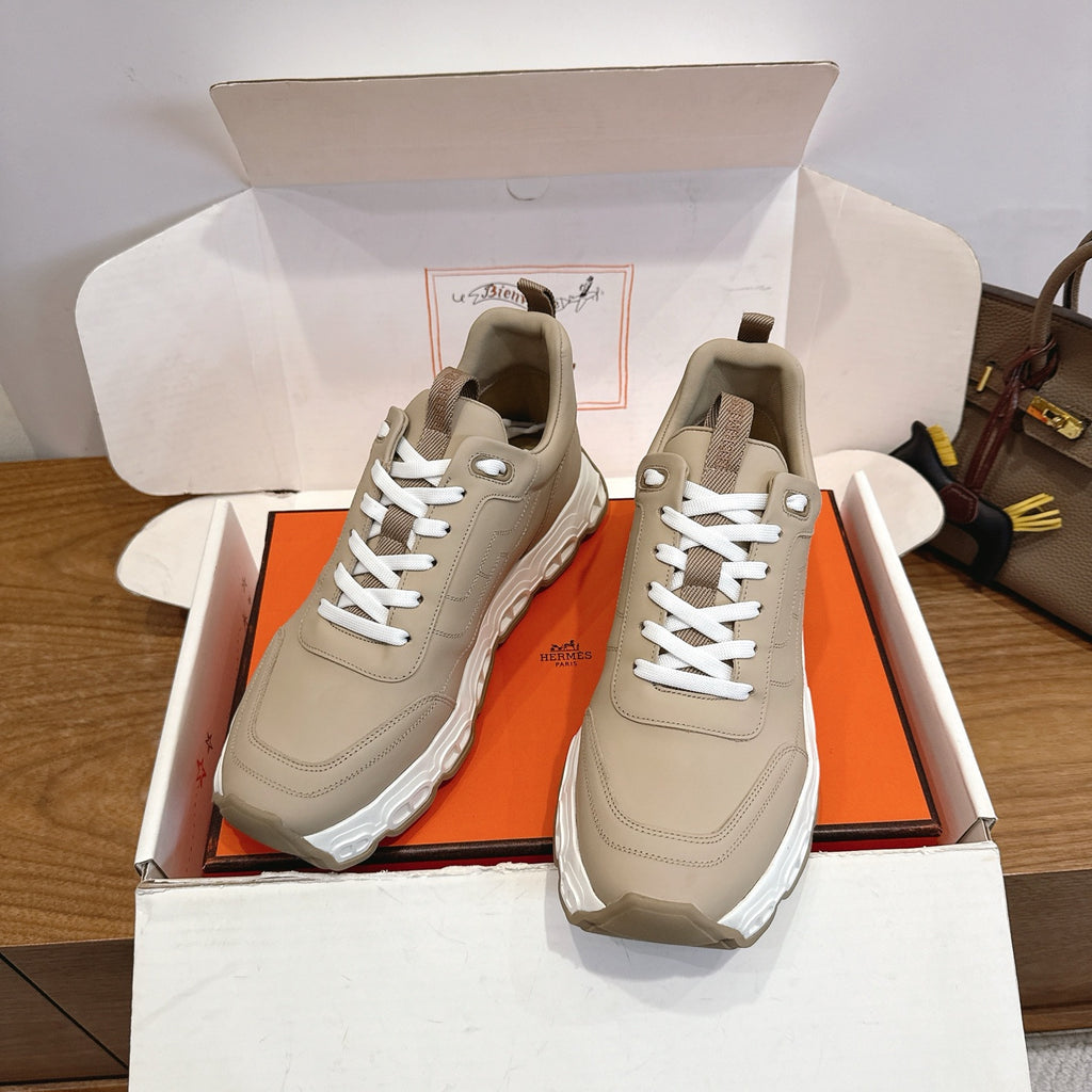 Beige lace-up sneakers with thick white sole, shown in open shoebox.