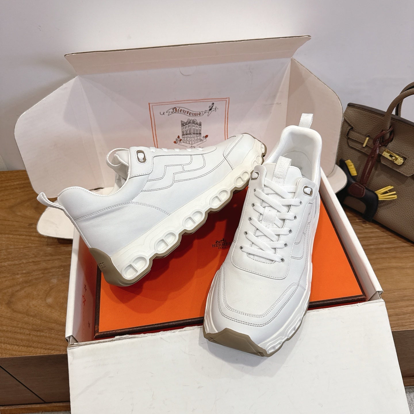 White lace-up sneakers with textured panel accents, chunky sole, Hermes style