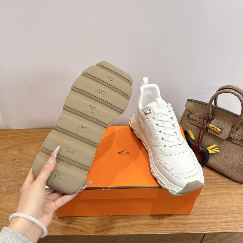 Sneakers outsole view, thick rubber tread and Hermes logo, white lace-up
