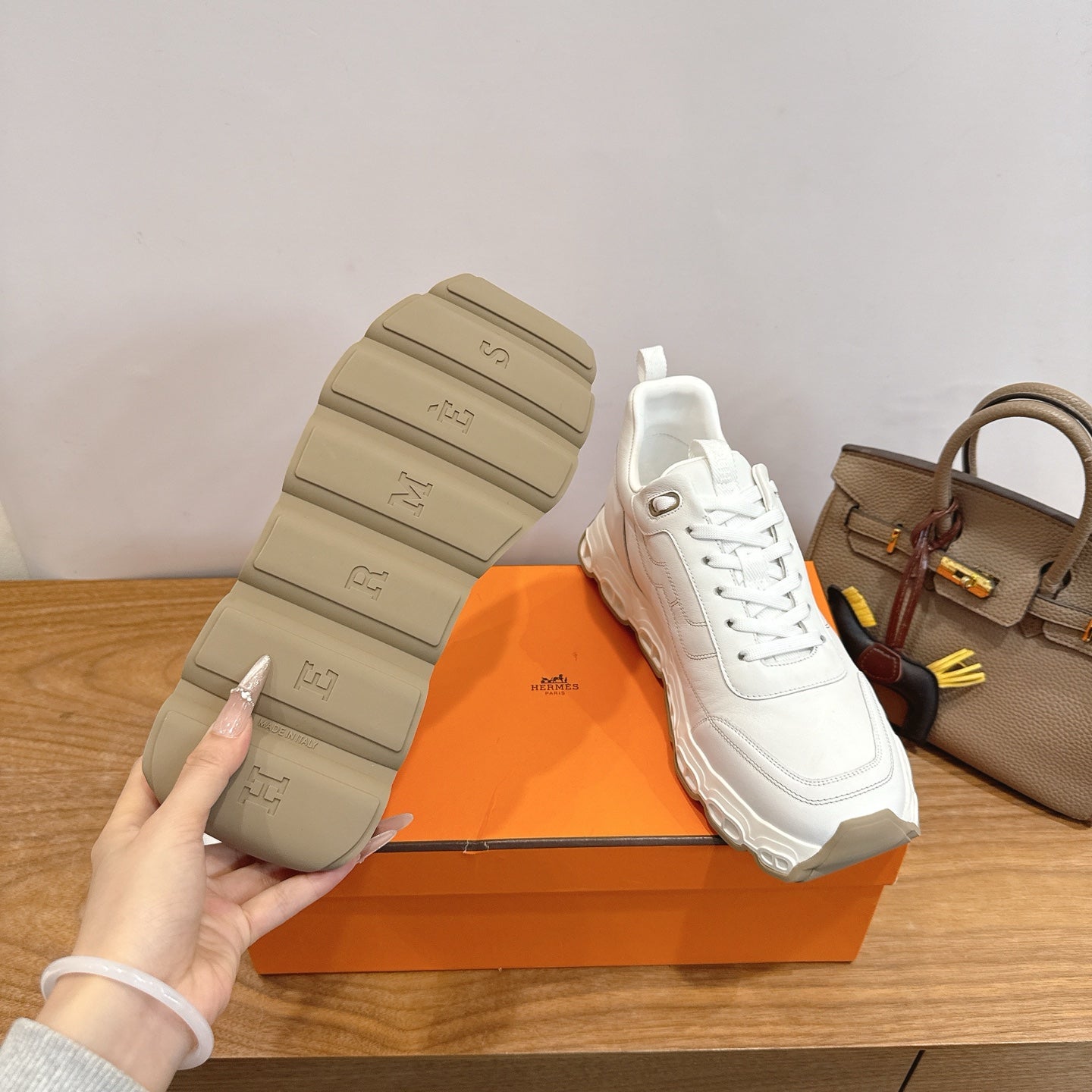 Sneakers outsole view, thick rubber tread and Hermes logo, white lace-up