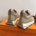 Beige Hermes sneakers with white sole, rear view showing heel logo.