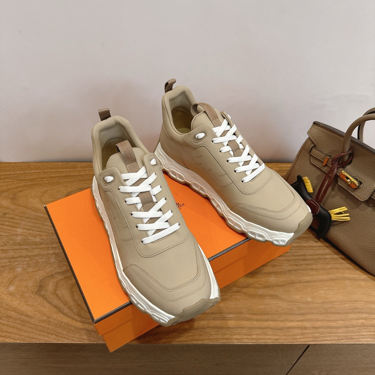 Beige lace-up sneakers with chunky white sole, front angle on shoebox.