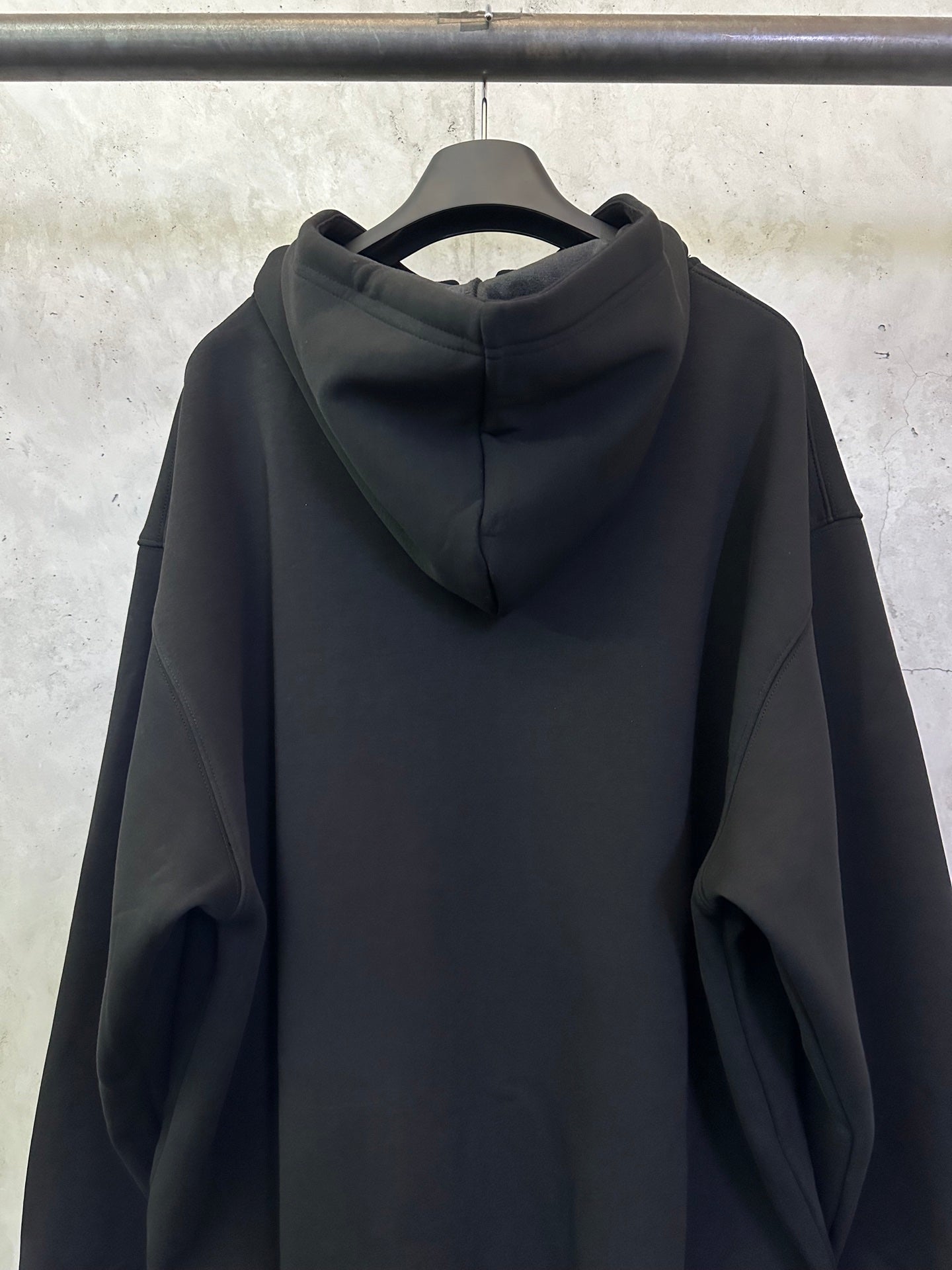 Balenciaga black zip-up hoodie with hood and back panel, shown from behind.