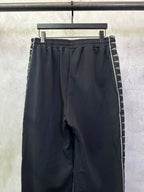 Black track pants with gathered elastic waistband and side stripe