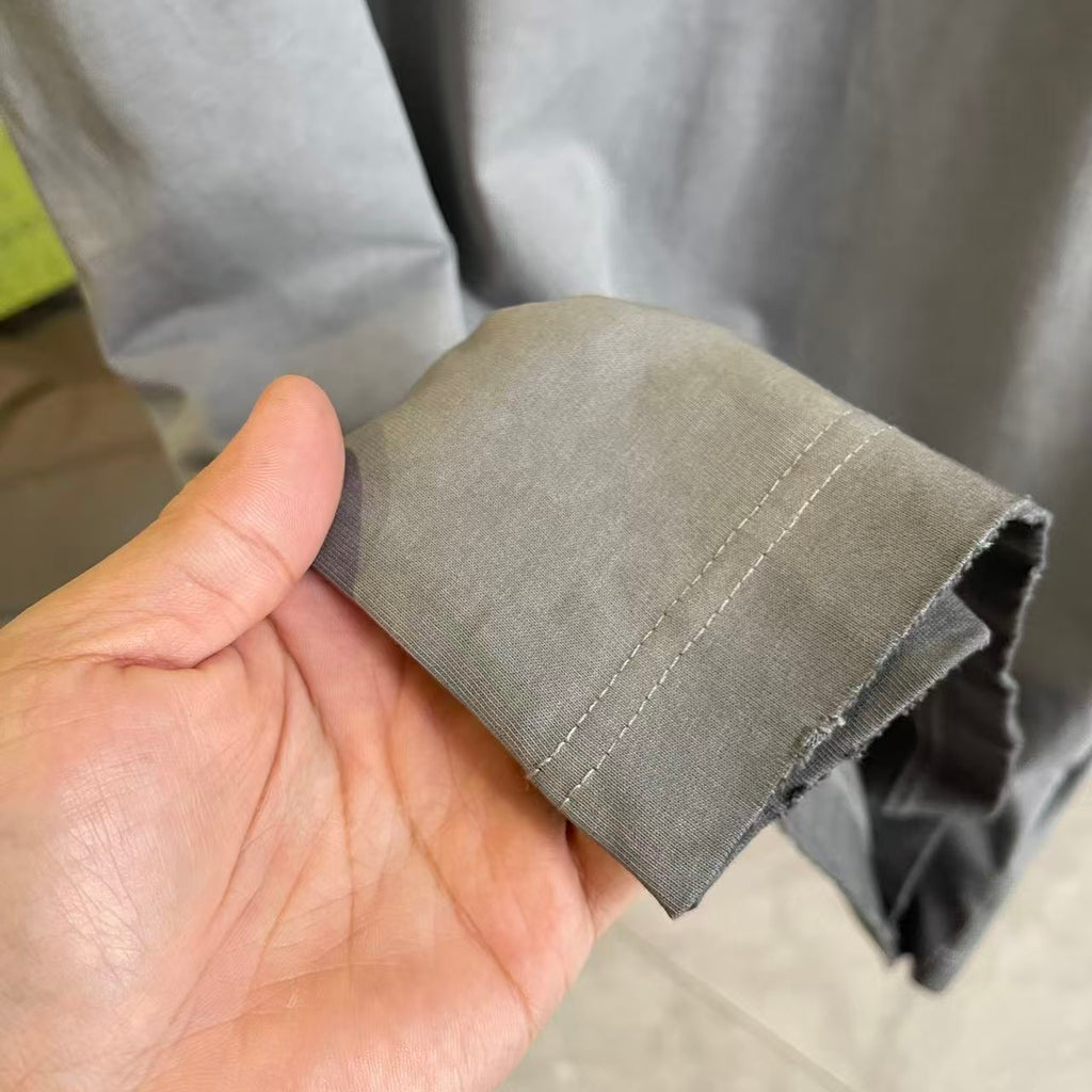 Gray T-shirt fabric cuff edge with stitched hem, held in hand