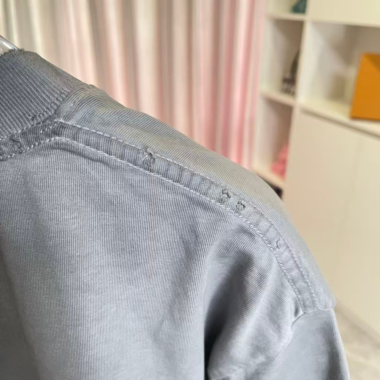 Gray T-shirt sleeve and shoulder seam with visible topstitching