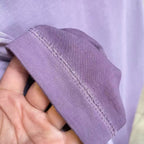 Lavender T-shirt sleeve hem with visible stitching held in hand