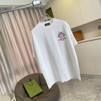 White short-sleeve T-shirt with pink and black cross logo, front view