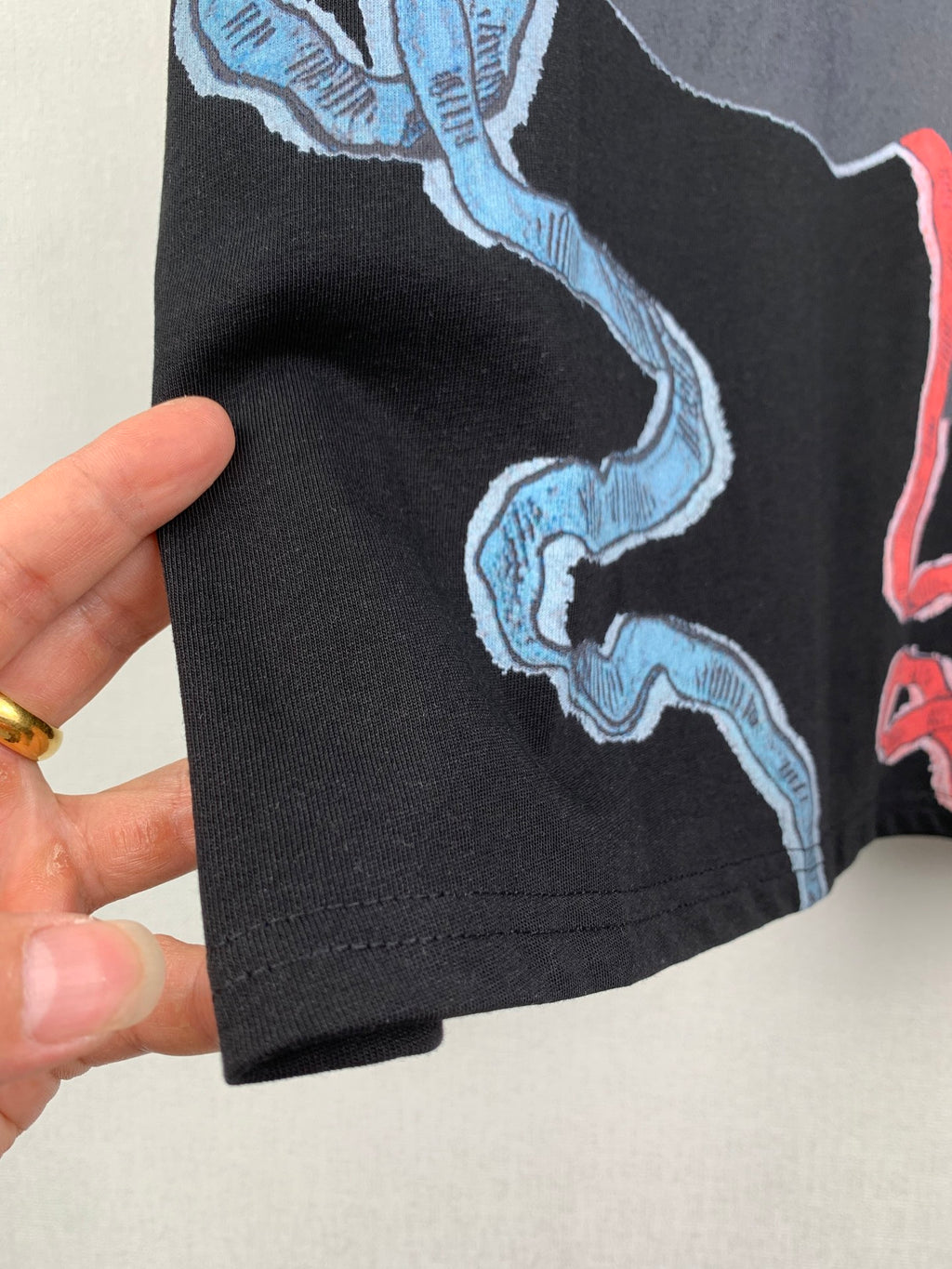 Louis Vuitton black T-shirt hem detail with blue wave and red trim graphic