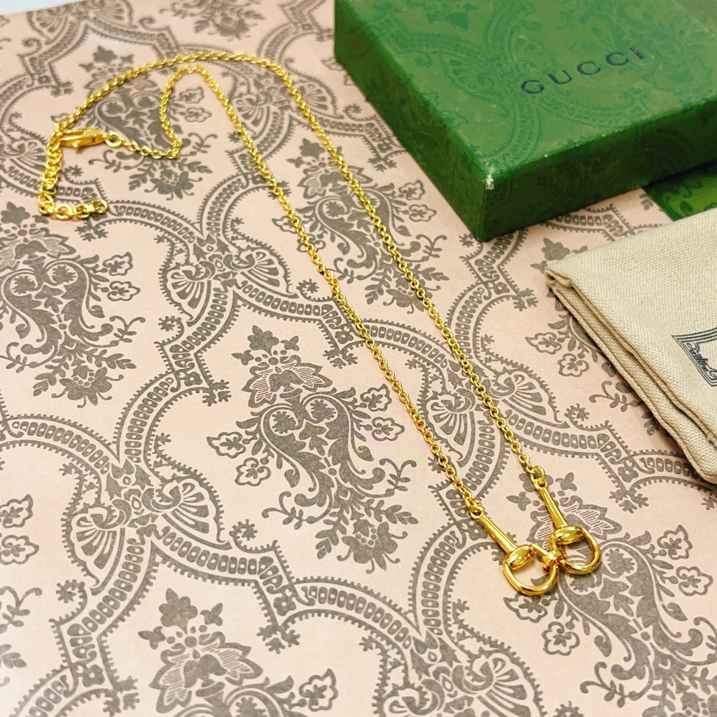 Gold-tone double-strand necklace with heart-shaped clasp on patterned fabric