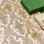 Gold-tone double-strand necklace with heart-shaped clasp on patterned fabric