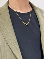 Gold-tone necklace with heart-shaped link pendant worn over a dark top