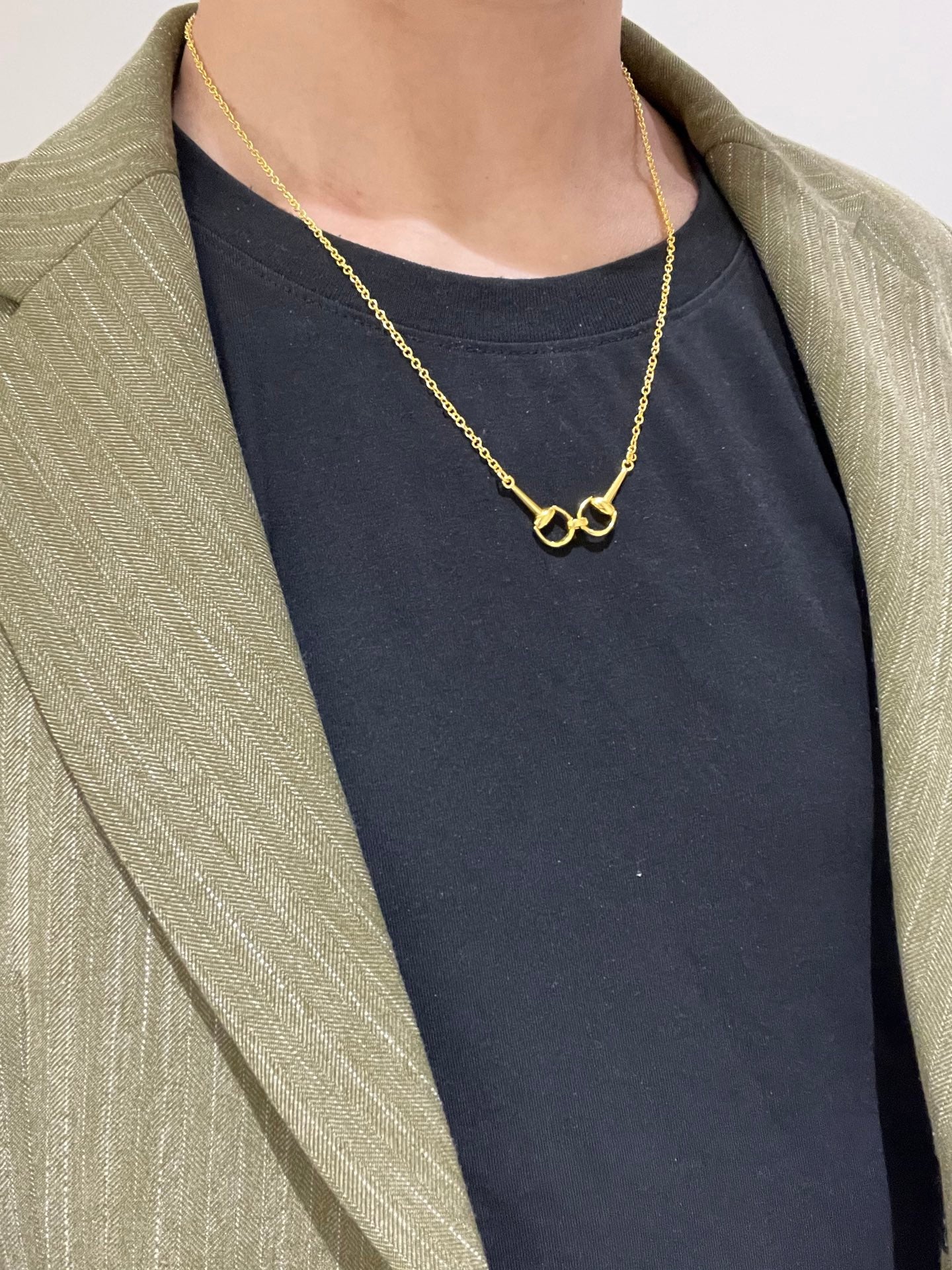 Gold-tone necklace with heart-shaped link pendant worn over a dark top