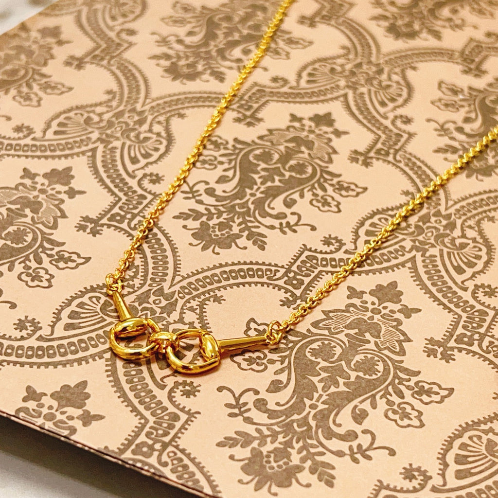 Gold-tone necklace center with three heart-shaped links on patterned fabric