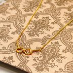 Gold-tone necklace center with three heart-shaped links on patterned fabric