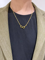 Gold-tone necklace with heart-shaped clasp worn with a dark top and light blazer