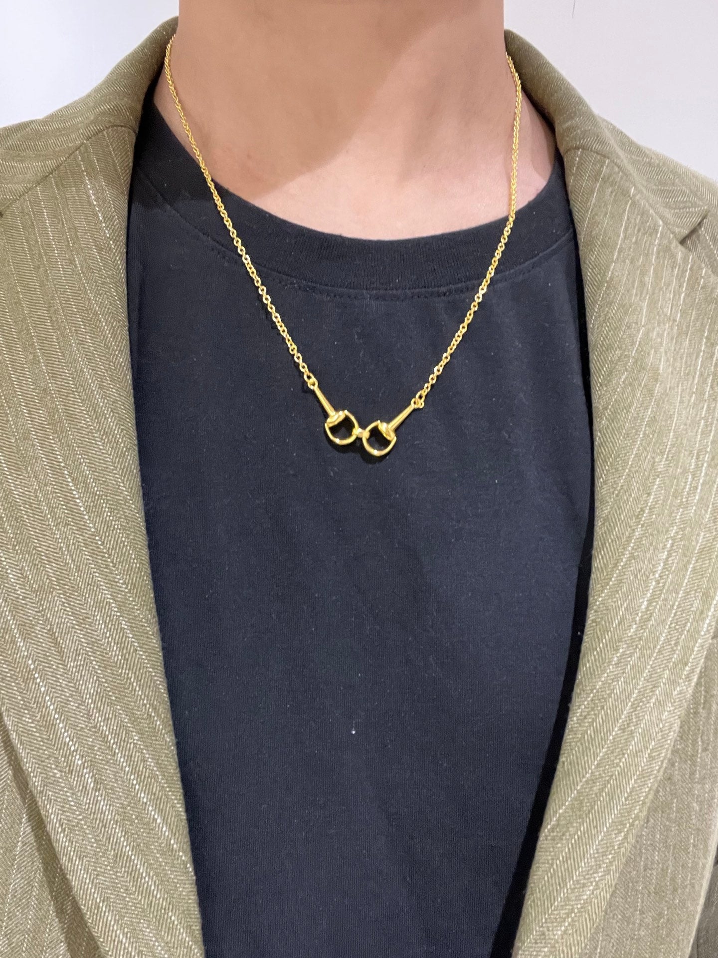 Gold-tone necklace with heart-shaped clasp worn with a dark top and light blazer