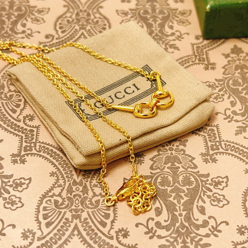 Gold-tone necklace with heart-link clasp and charm detail on patterned cloth