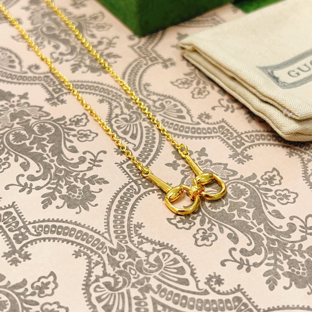 Gold-tone necklace with linked heart charms and clasp on patterned fabric