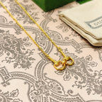 Gold-tone necklace with linked heart charms and clasp on patterned fabric