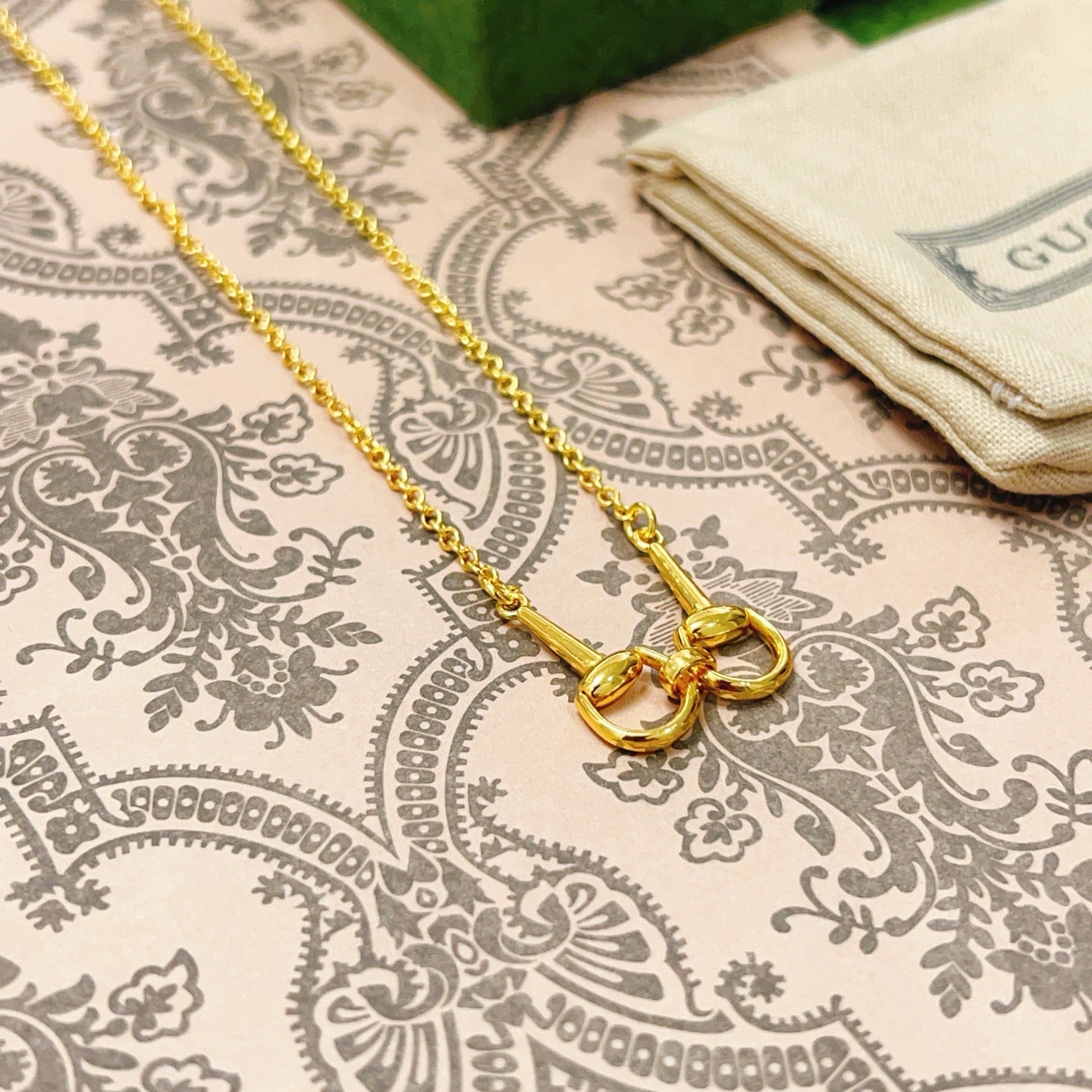 Gold-tone necklace with linked heart charms and clasp on patterned fabric