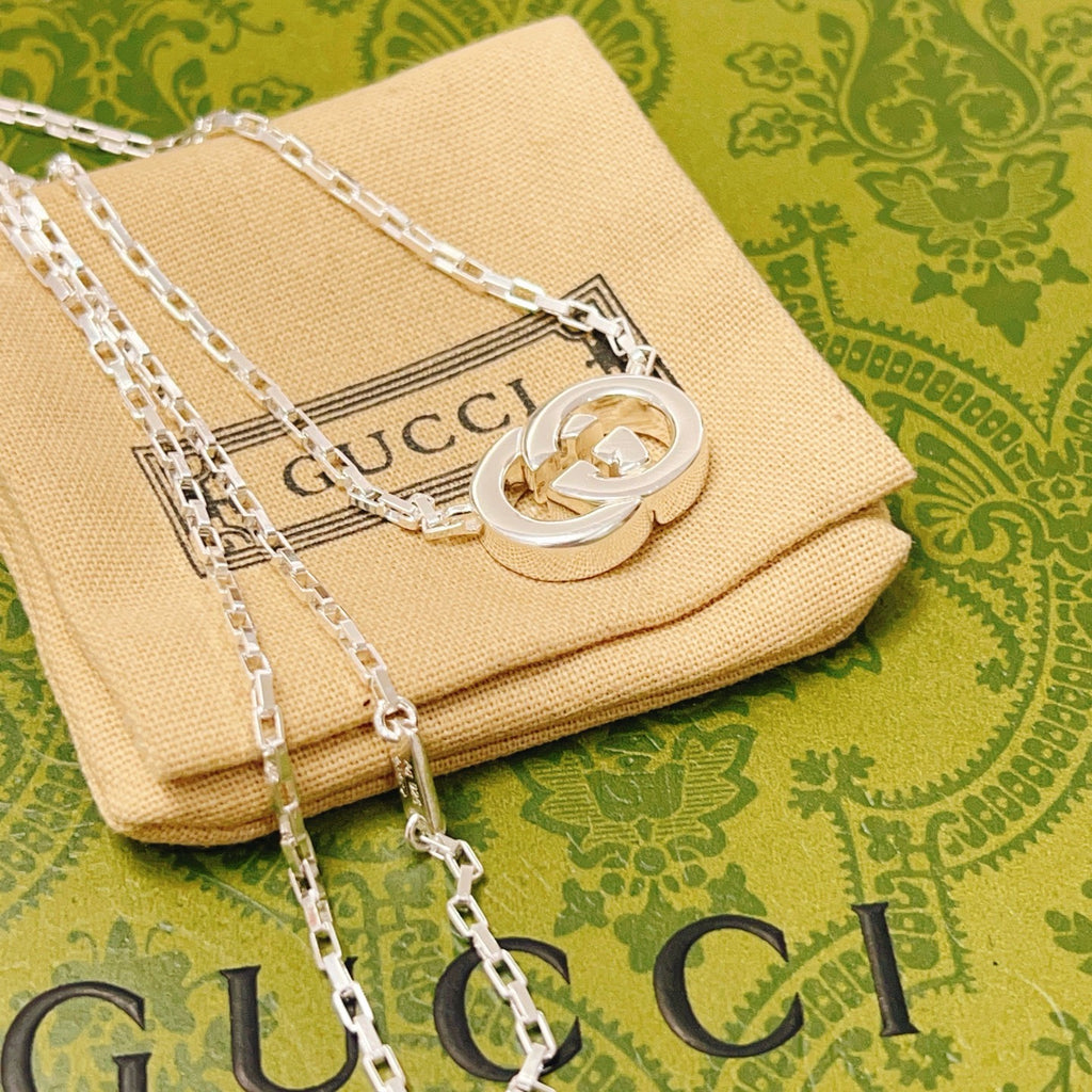 Gucci silver-tone GG pendant necklace on beige fabric pouch