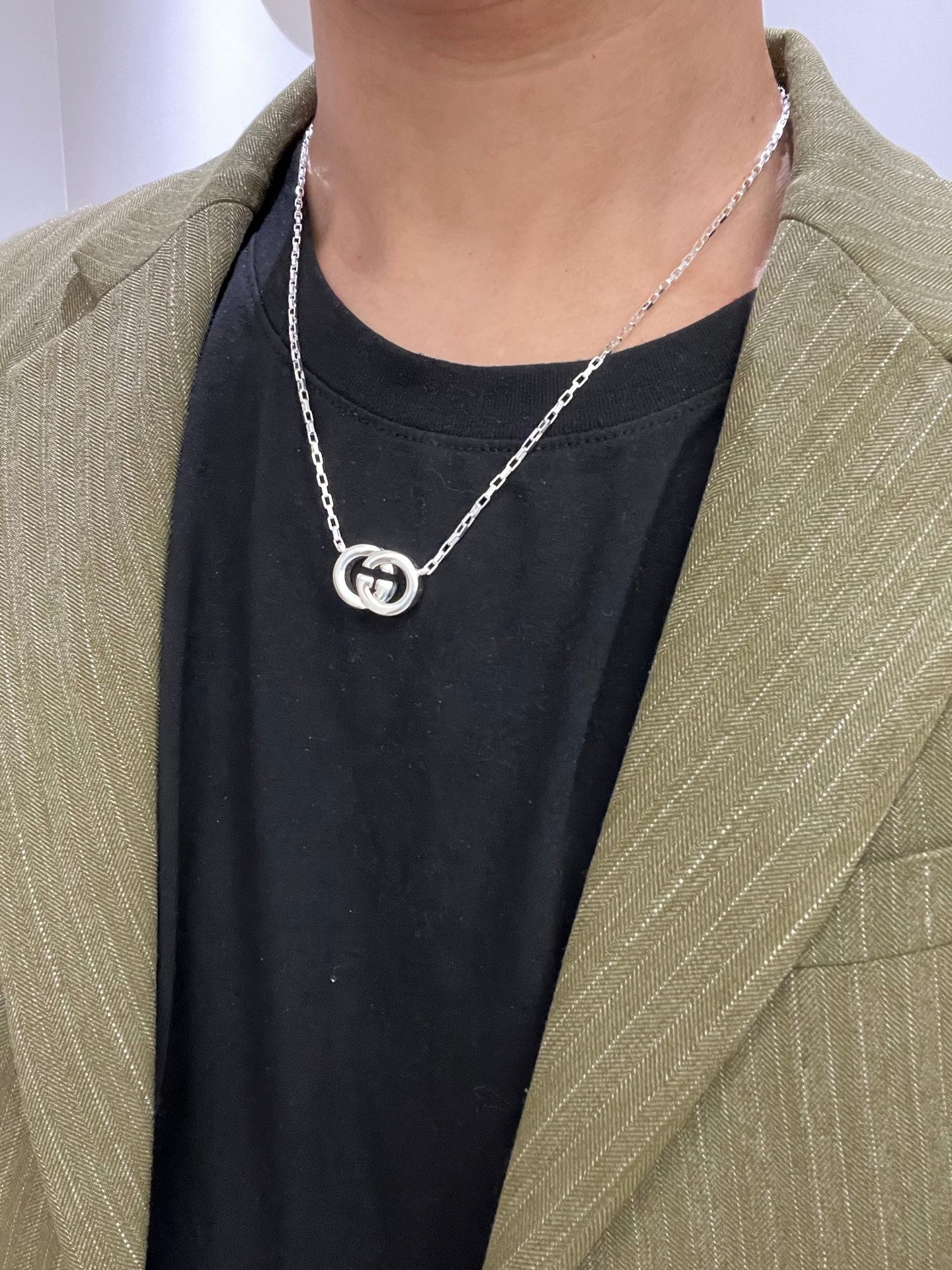 Gucci silver-tone GG pendant necklace worn with dark top and green blazer