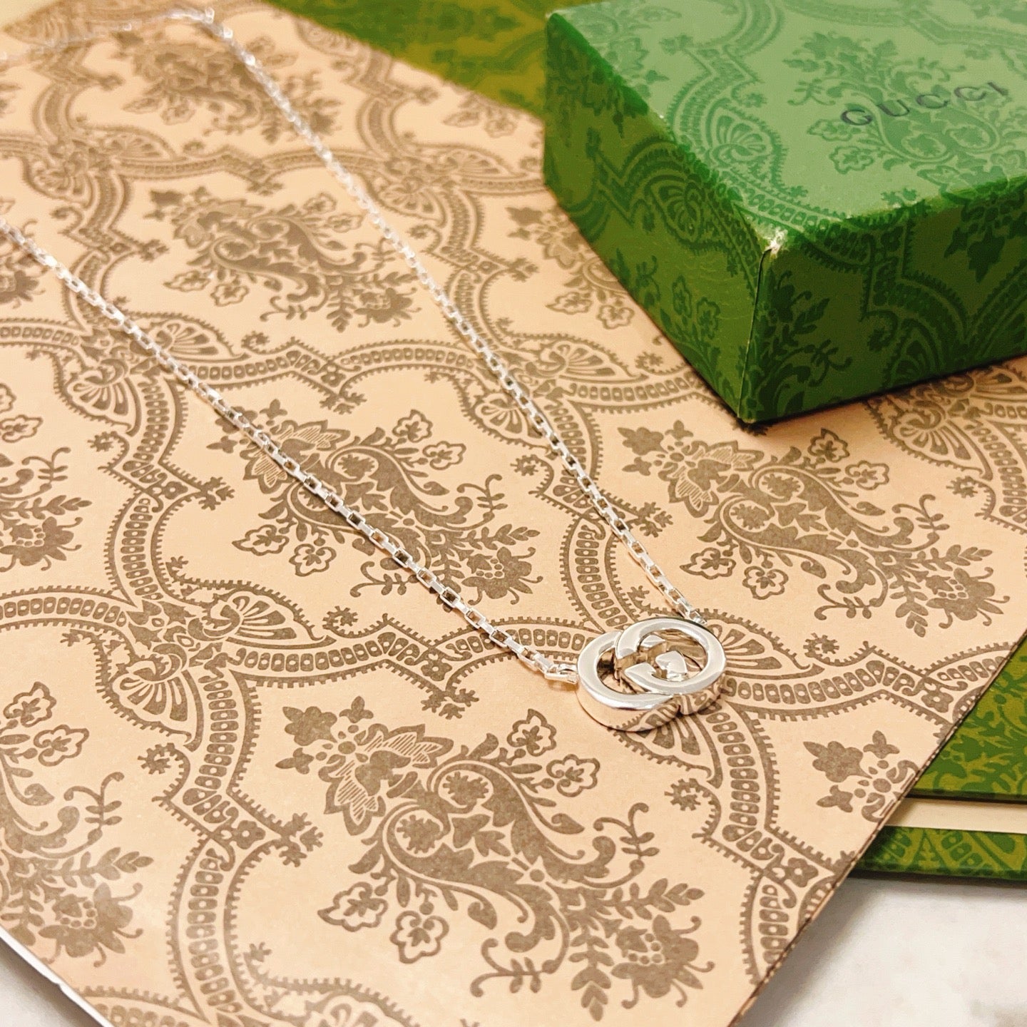 Gucci silver-tone GG pendant necklace with round emblem on patterned cloth