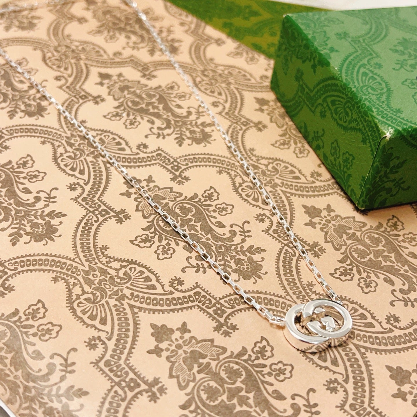 Gucci silver-tone GG pendant necklace on patterned fabric
