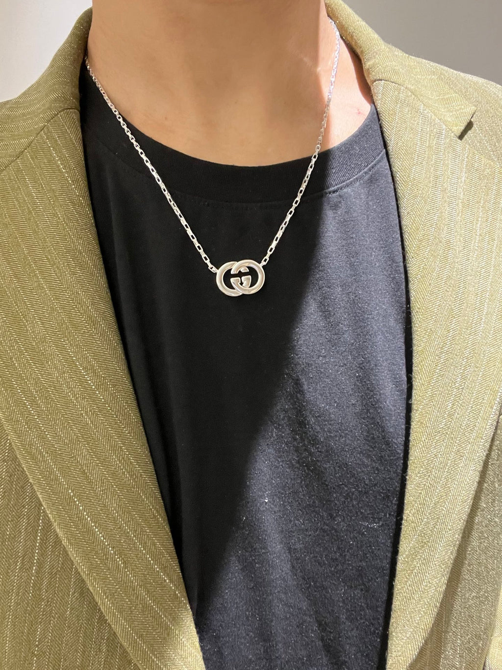 Gucci silver-tone GG pendant necklace worn with black top and light blazer