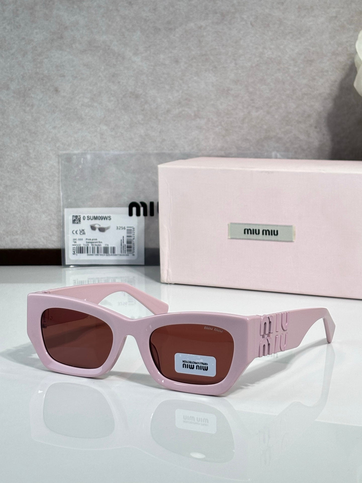 Pink oversized sunglasses with brown tinted lenses and logo on side temples