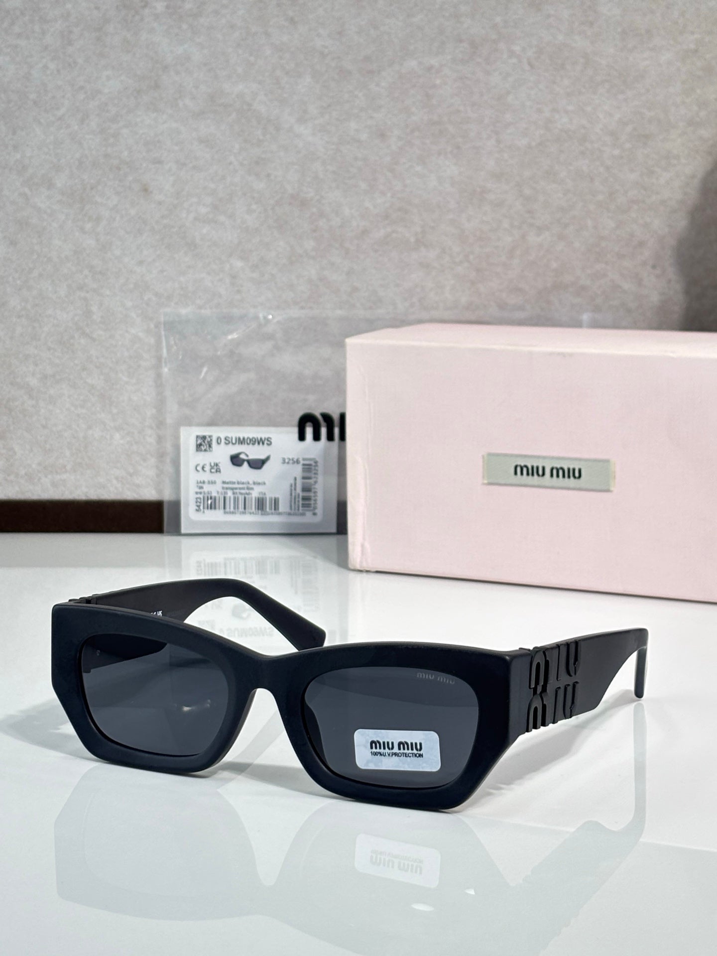 Black oversized sunglasses with dark tinted lenses and gold logo on side temples