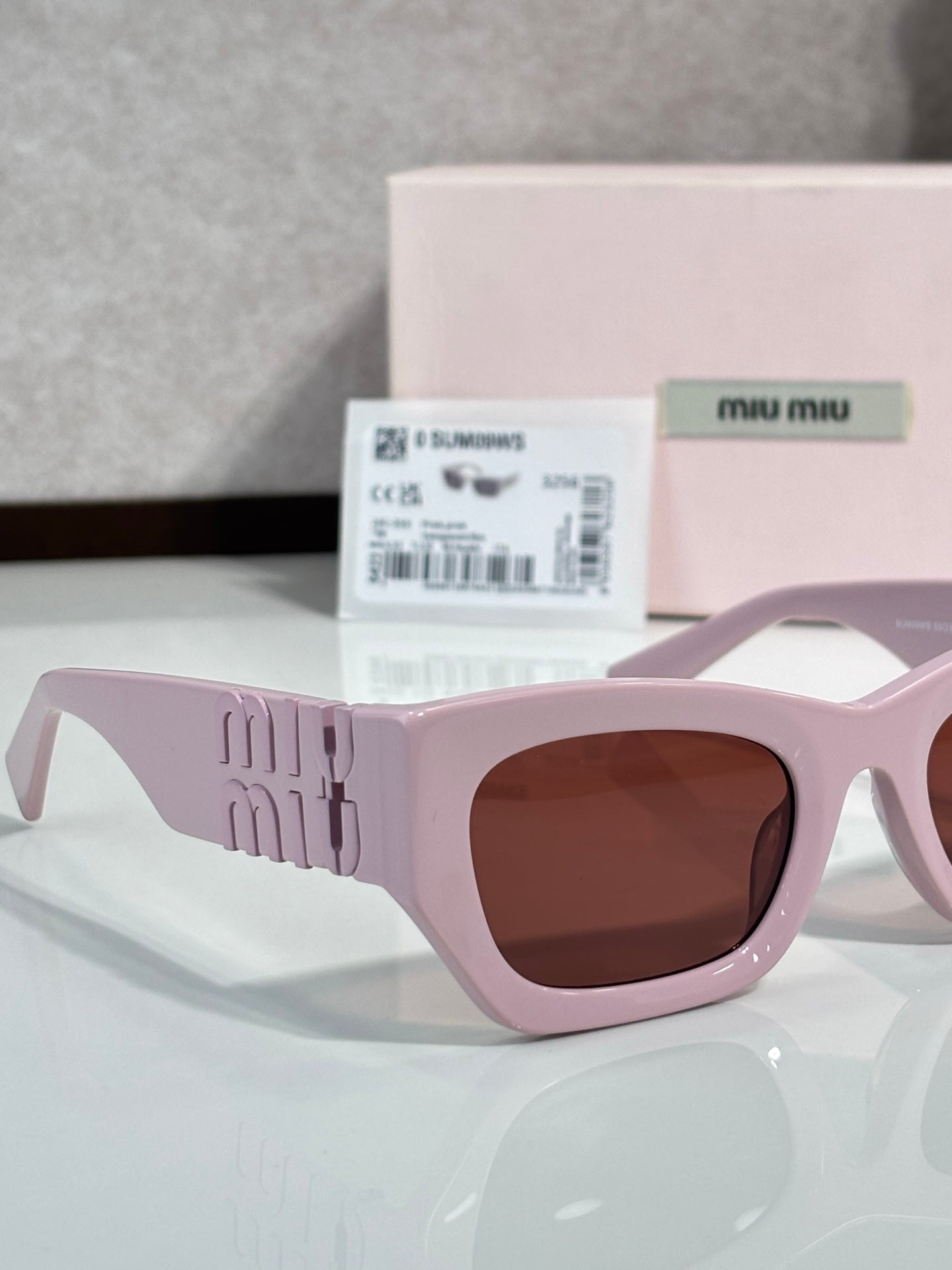 Light pink oversized sunglasses with brown tinted lenses and geometric logo detail