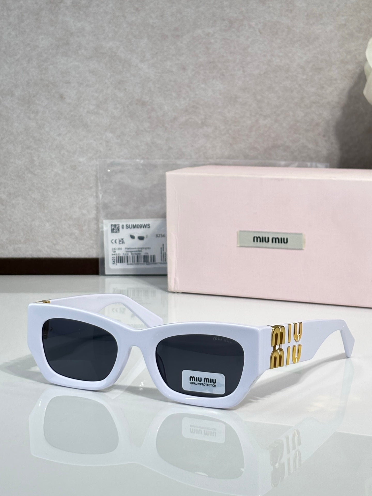 White oversized sunglasses with dark tinted lenses and gold logo temple detail