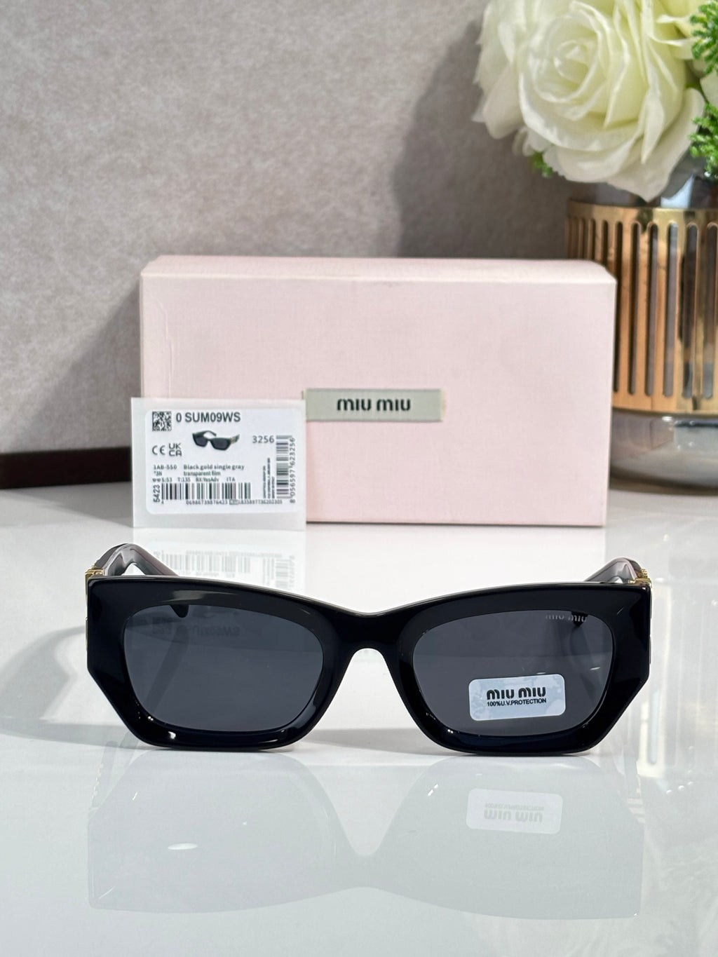 Black oversized sunglasses with dark tinted lenses and miu miu logo on temple
