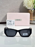 Black oversized sunglasses with dark tinted lenses and miu miu logo on temple