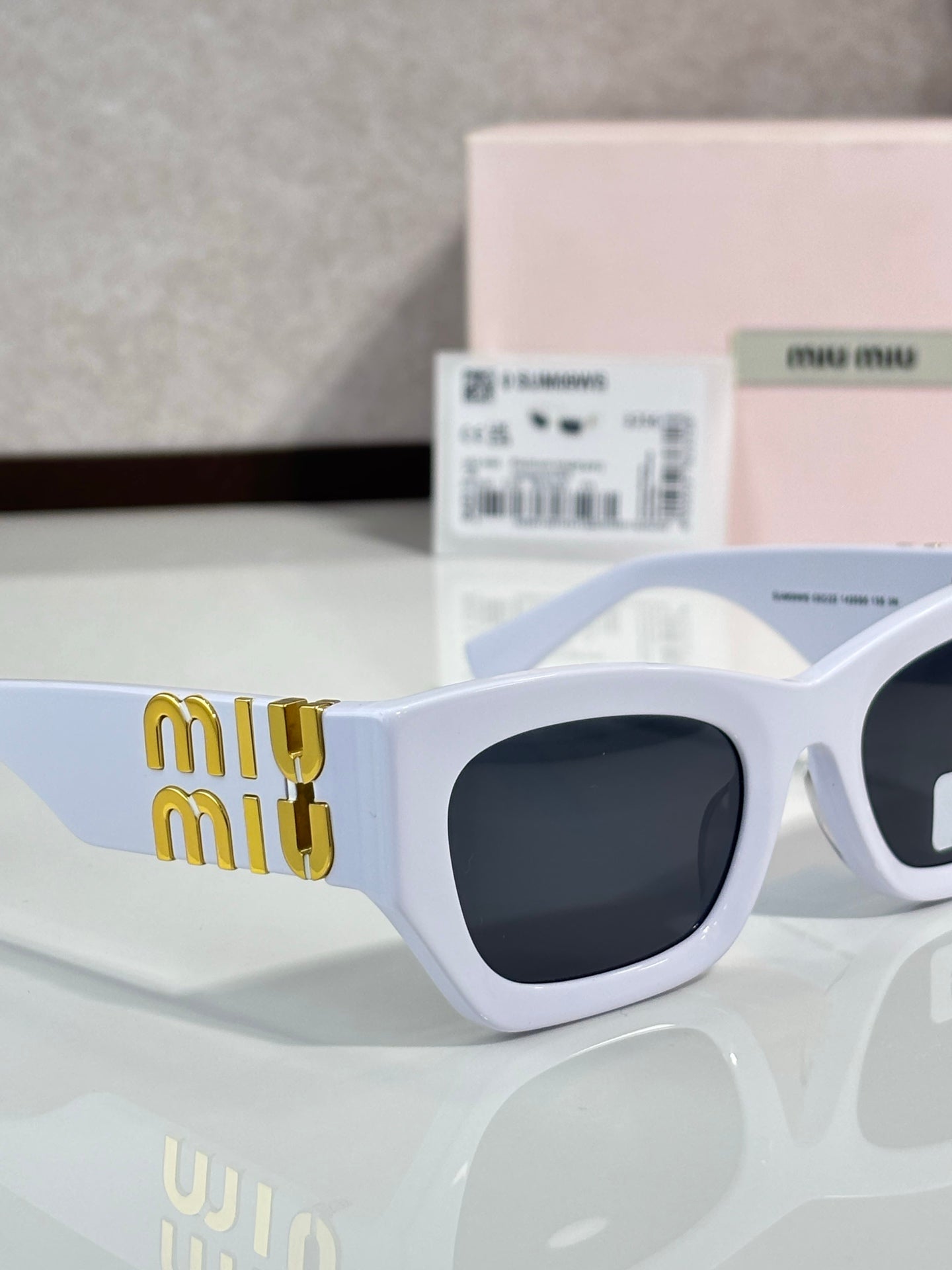 Light blue oversized sunglasses with dark tinted lenses and gold miu miu logo