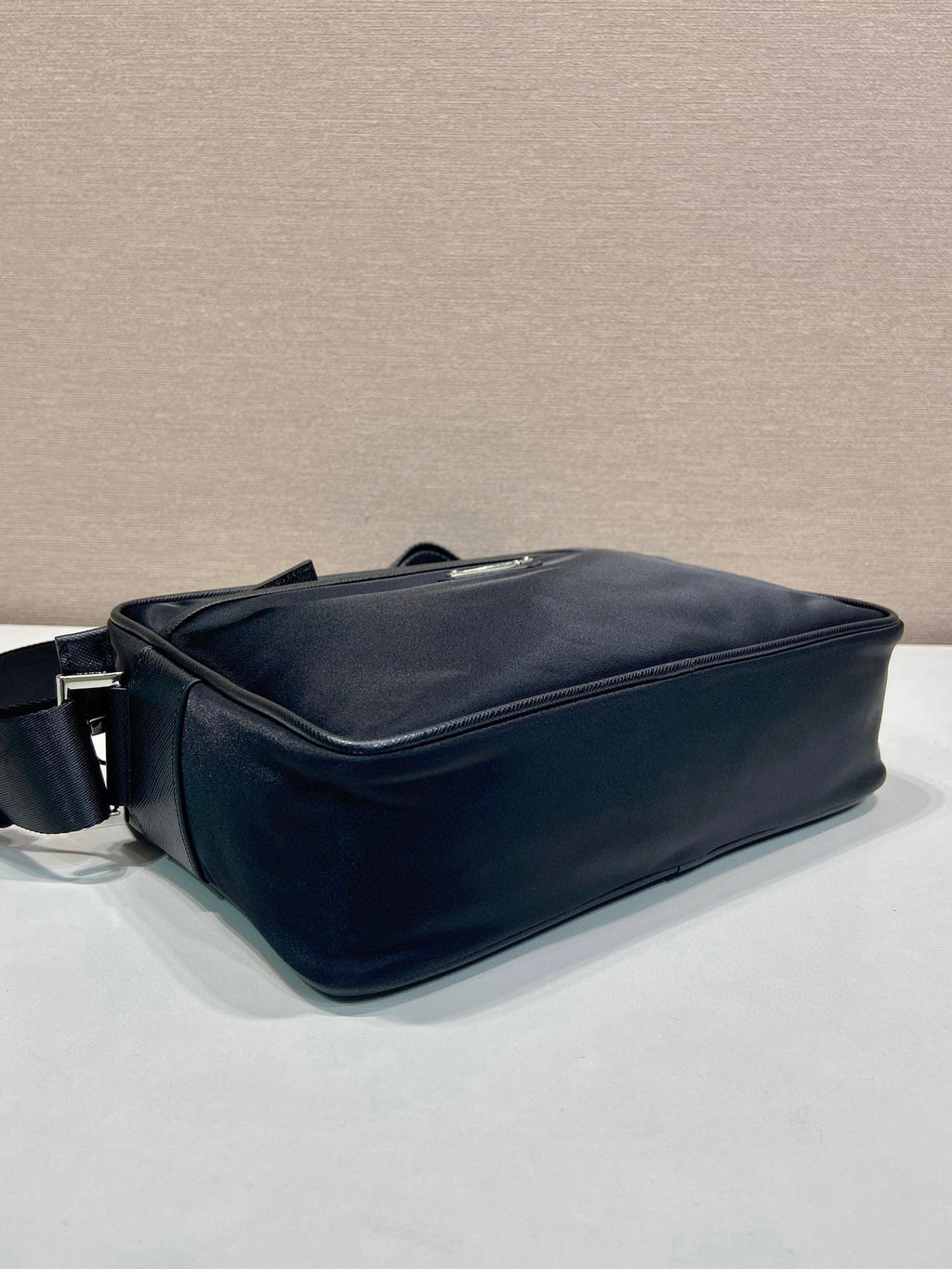 Prada crossbody bag side view with curved base and zipper trim, dark blue
