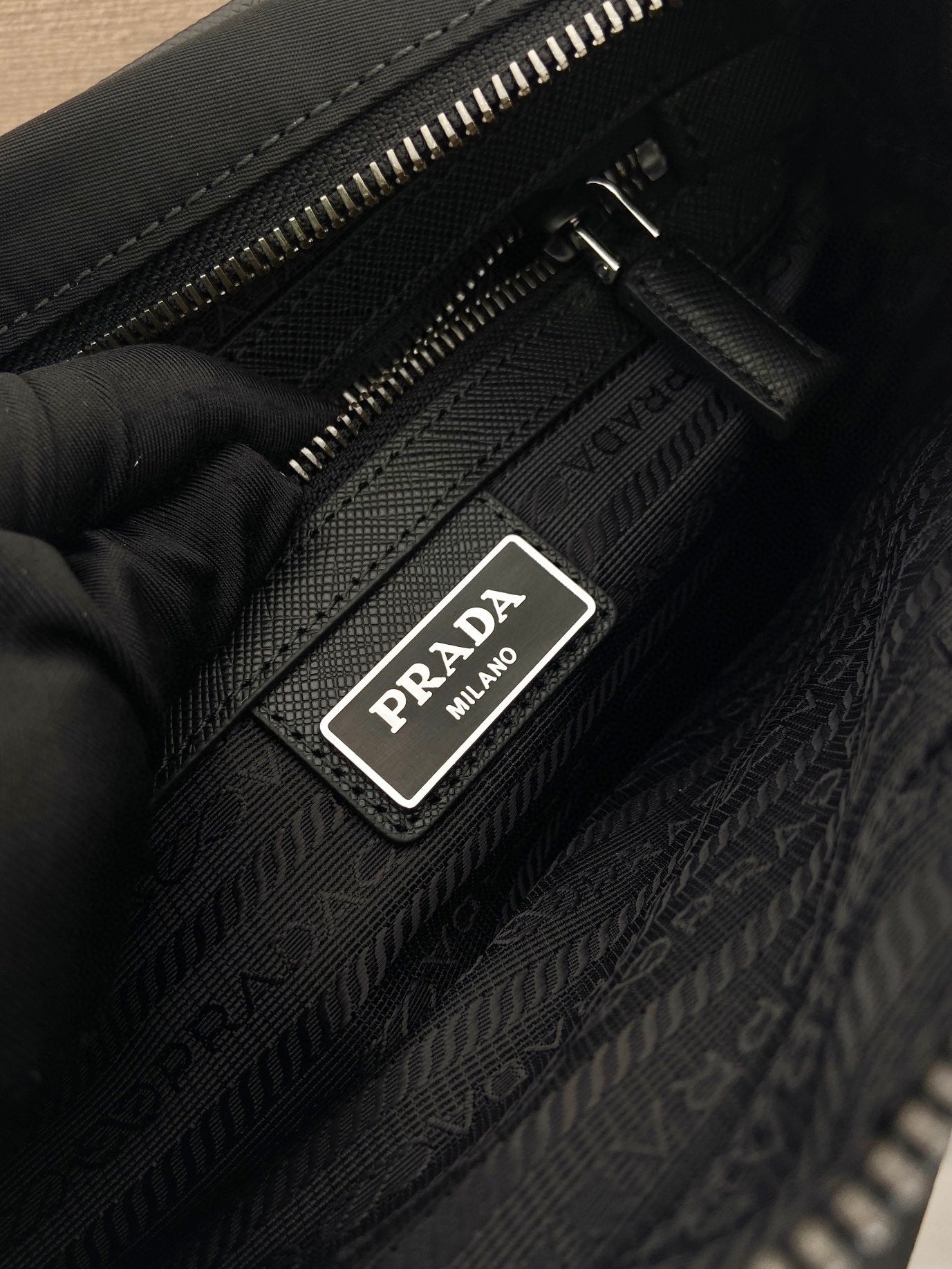 Prada interior label on dark patterned bag lining with zipper, dark blue