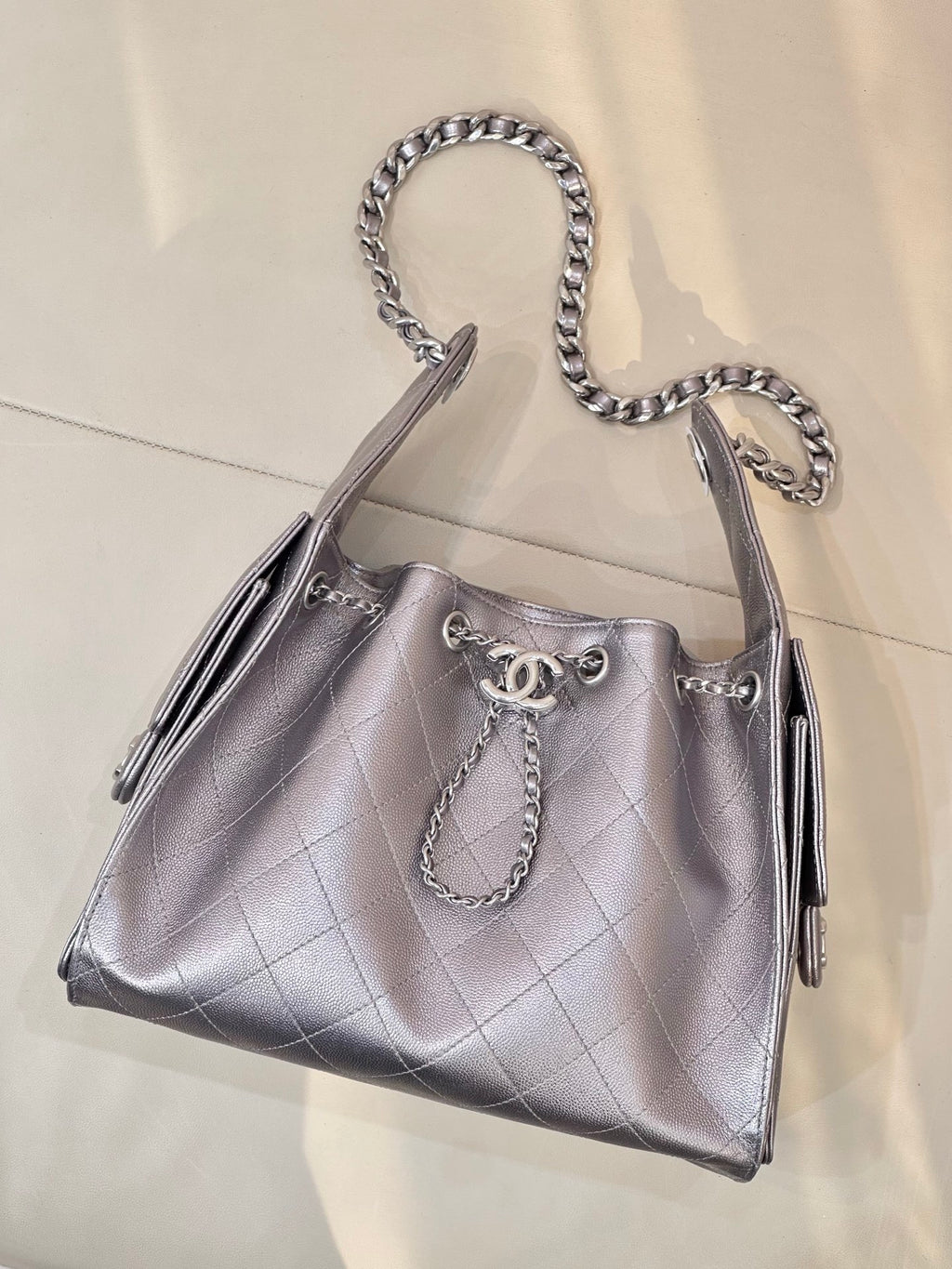 Quilted leather tote bag with chain handles, side tassels, and Chanel logo on front, silver