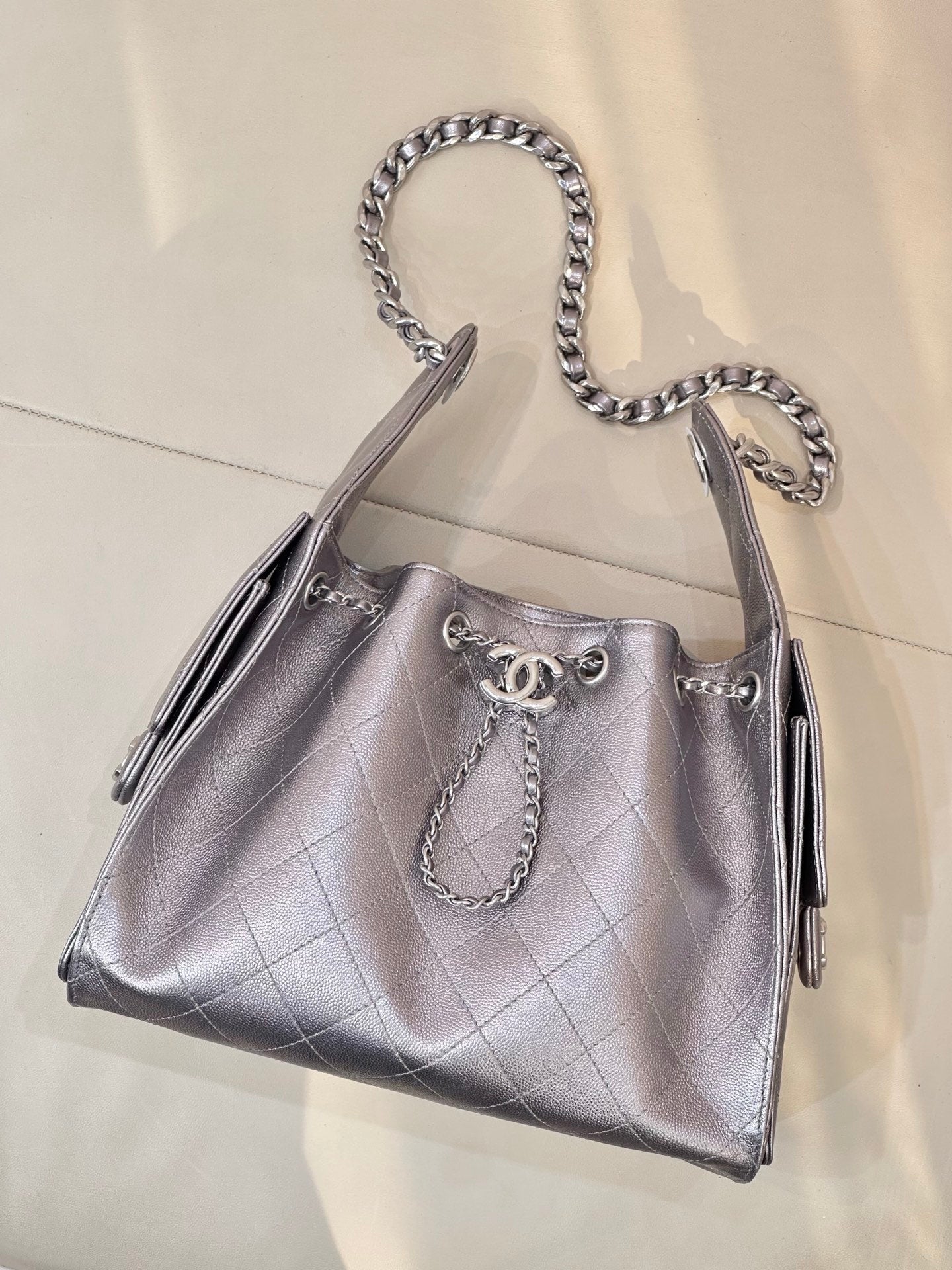 Quilted leather tote bag with chain handles, side tassels, and Chanel logo on front, silver