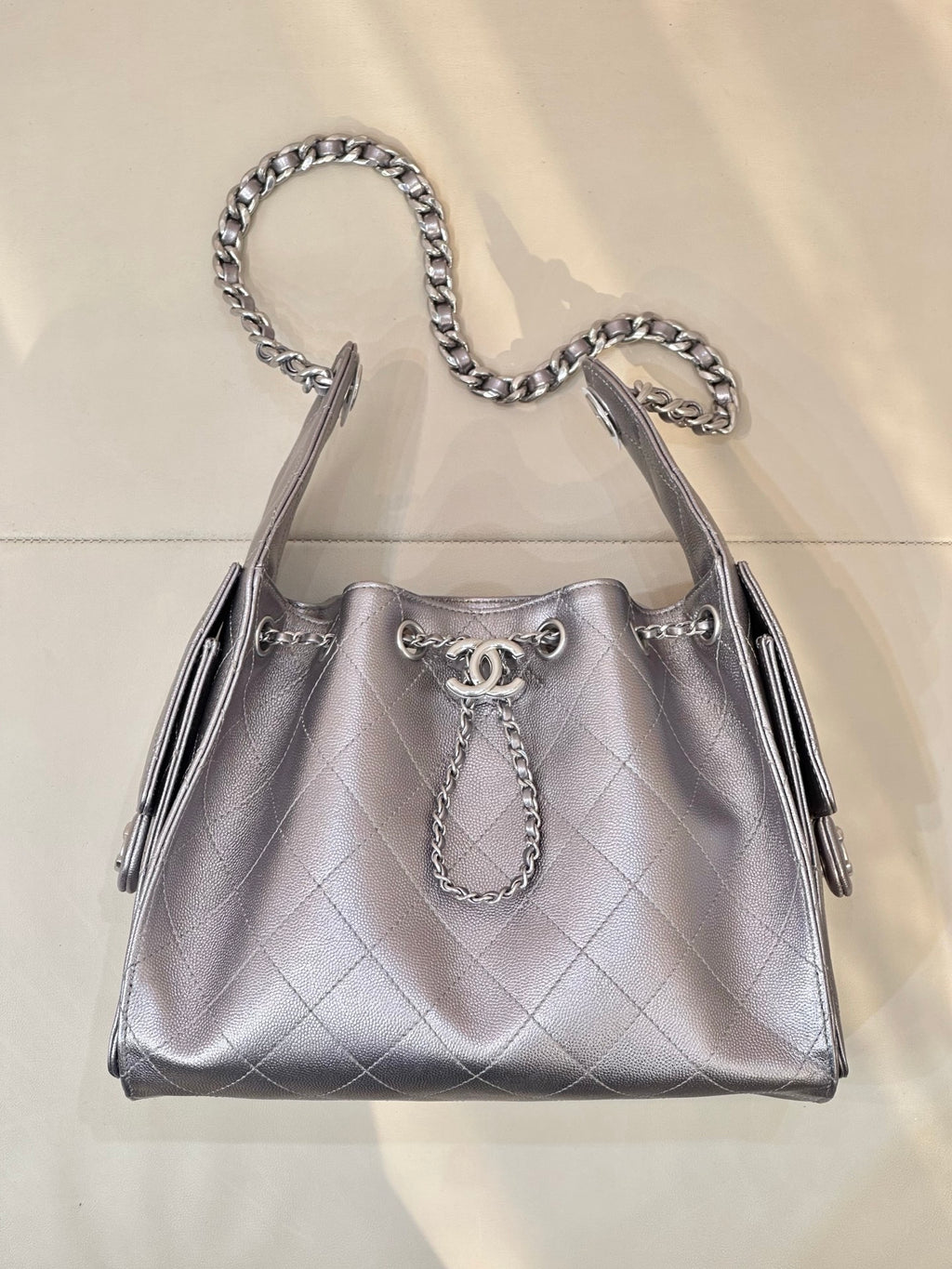 Quilted leather shoulder bag with chain top handles and Chanel logo charm, silver tone