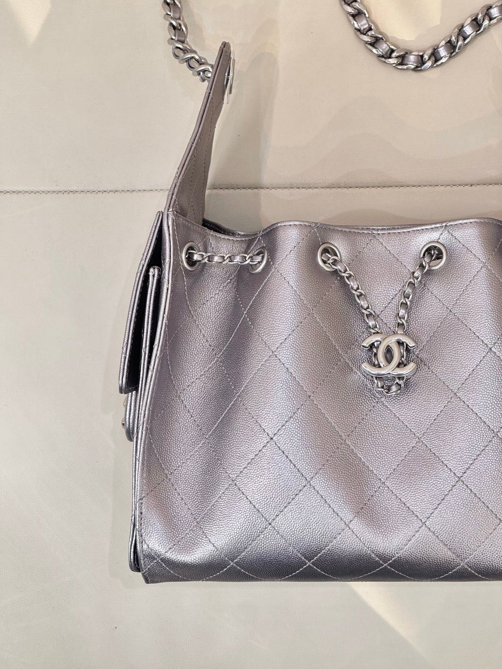 Quilted leather shoulder bag corner view with chain handles and Chanel CC charm, silver