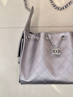 Quilted leather shoulder bag corner view with chain handles and Chanel CC charm, silver