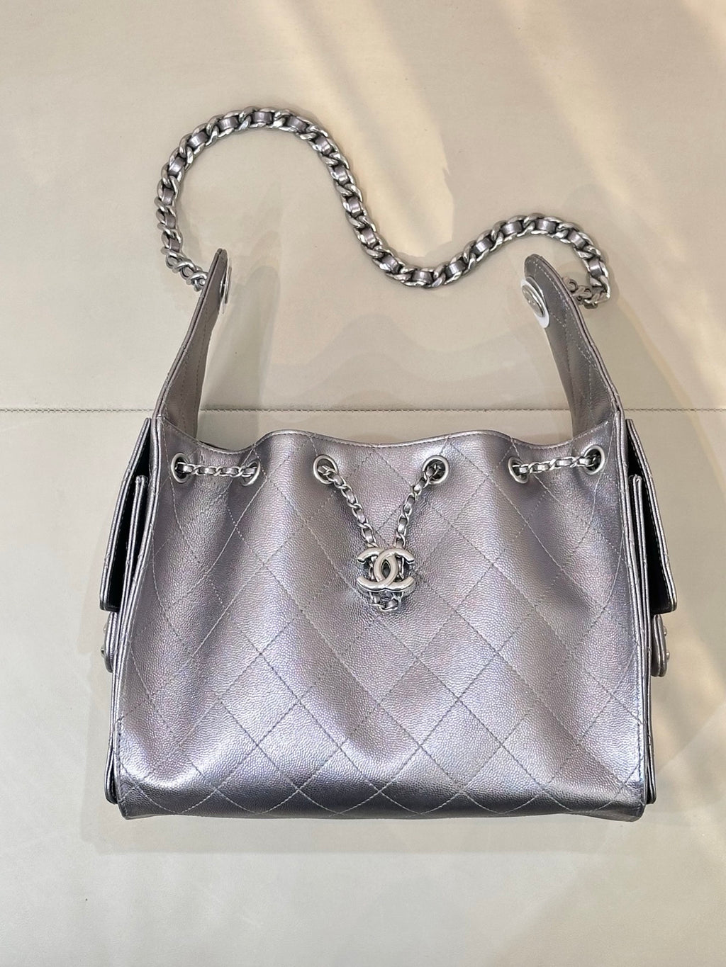 Quilted leather shoulder bag with chain handles, front Chanel CC charm, and side tabs, silver