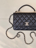 Dark navy quilted Chanel handbag with chain strap and top handle, logo detail