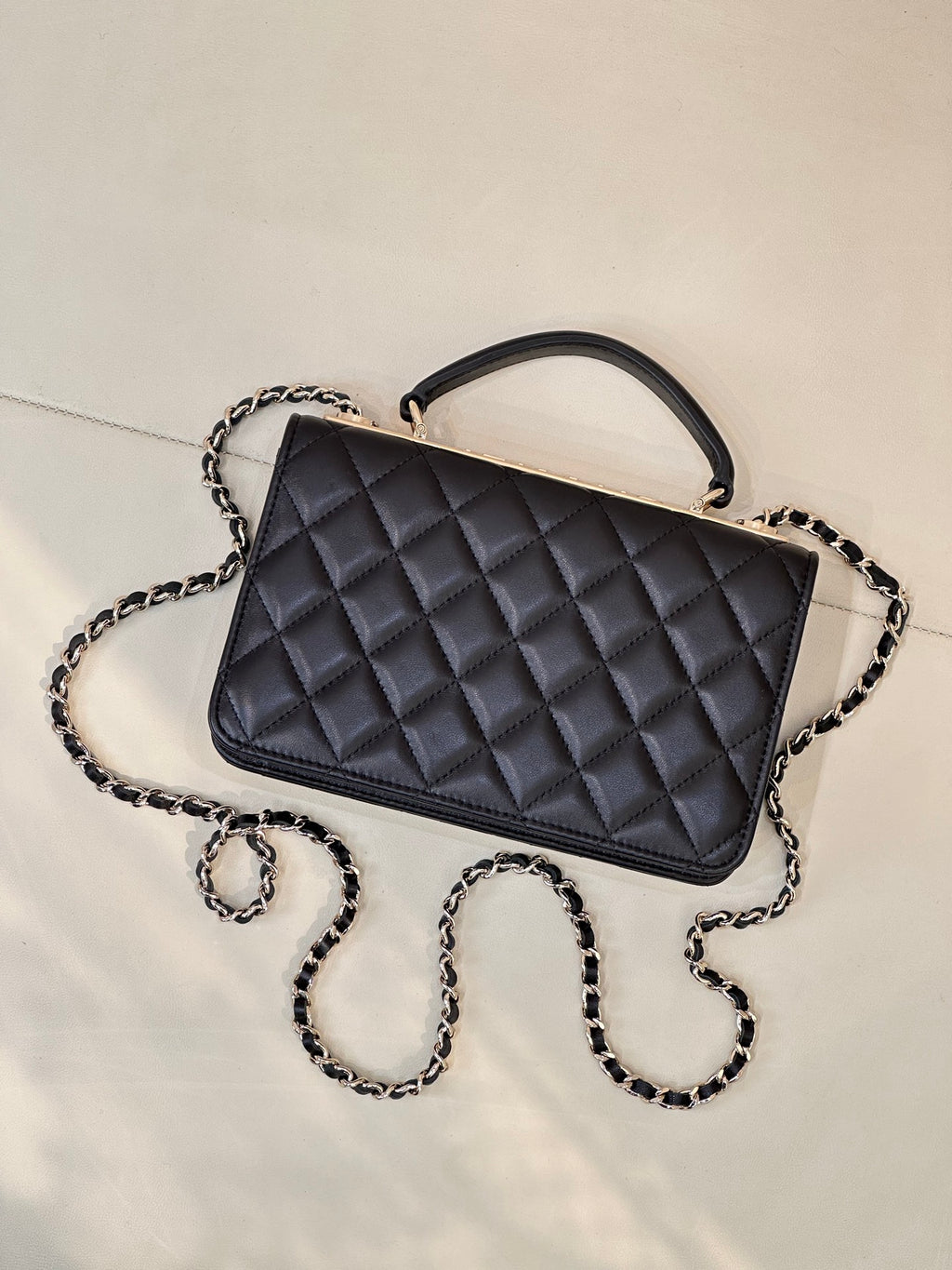 Dark navy quilted Chanel handbag with top handle and chain strap, angled view