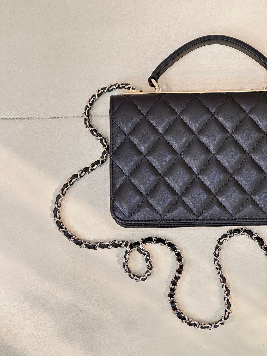 Dark navy quilted Chanel handbag with top handle and chain strap, close front angle